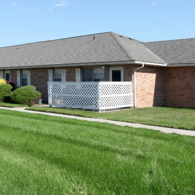 Exterior view of a single-story apartment complex with tidy landscaping and green grass.