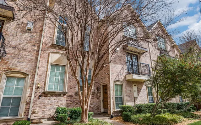 Brick Townhouse Exterior Exterior view of a brick townhouse with a bare tree and greenery in front.