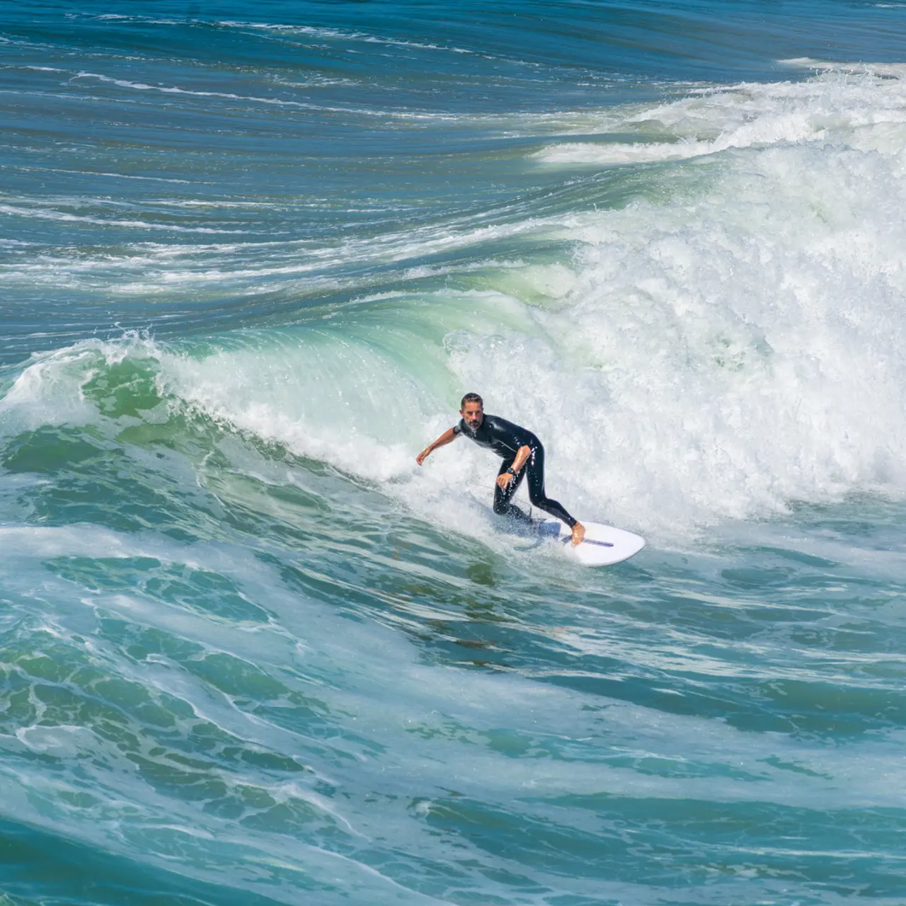 A surfer riding a wave in the ocean, showcasing dynamic movement and skill while balancing on a surfboard.
