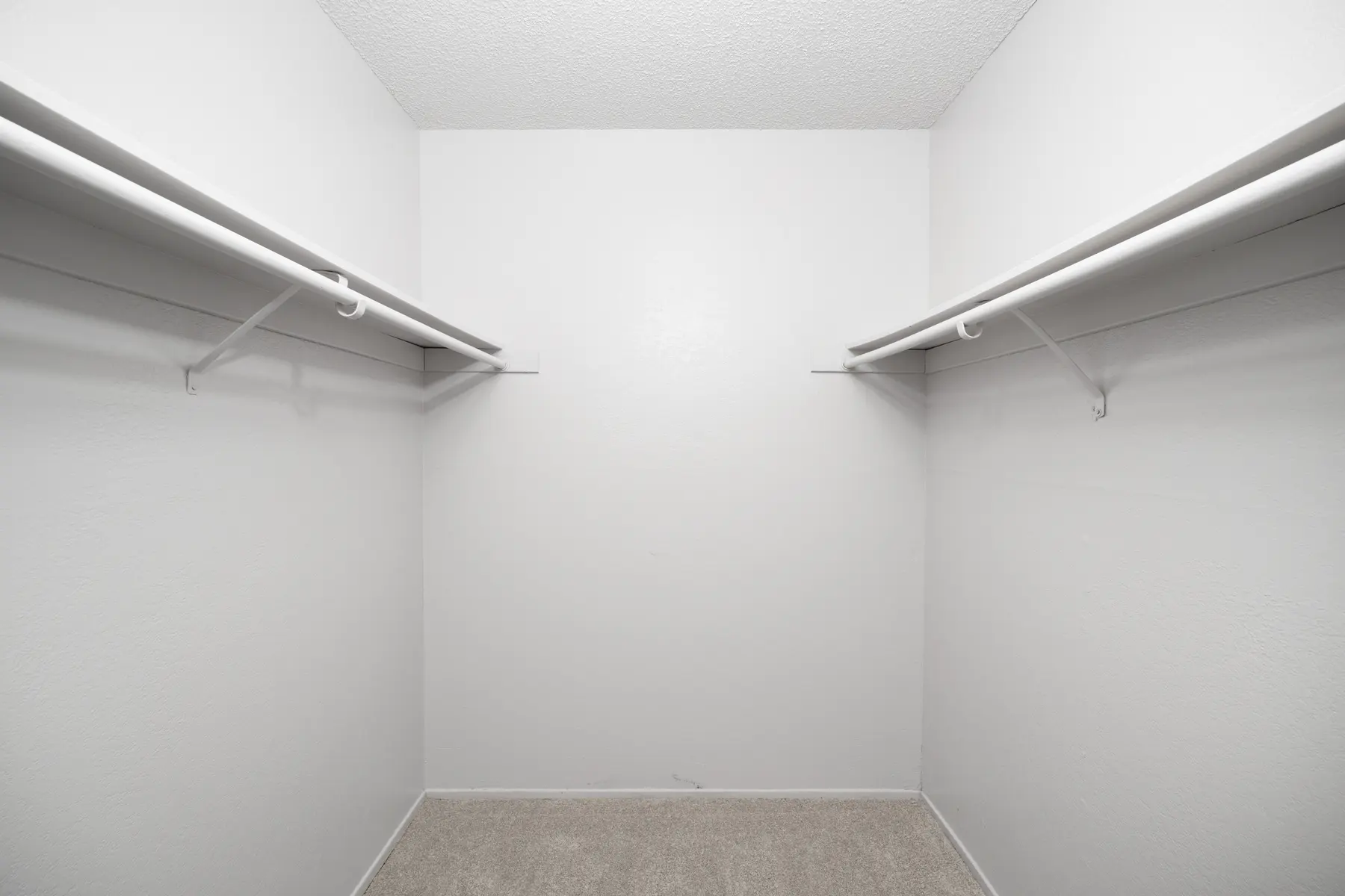 Empty closet with white walls and two hanging rods.