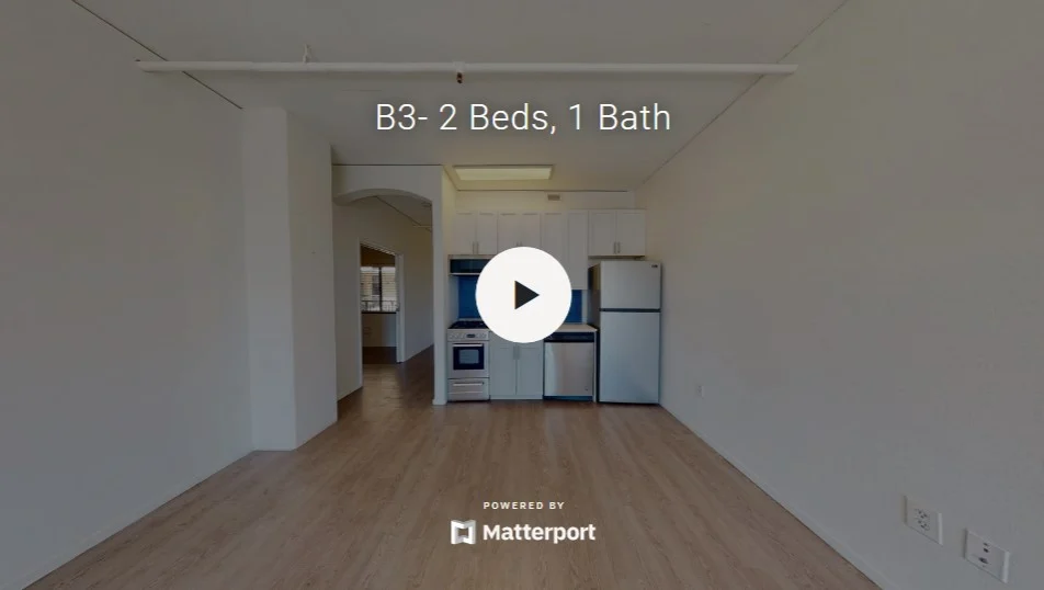 Interior view of an apartment featuring a kitchen area with appliances and a spacious living area.