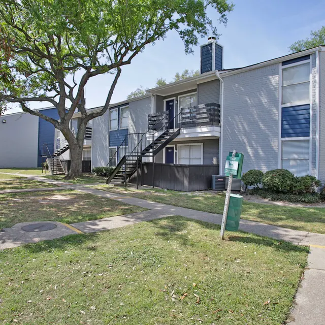Apartment Complex in a Green Setting View of a two-story apartment complex surrounded by green grass and trees.
