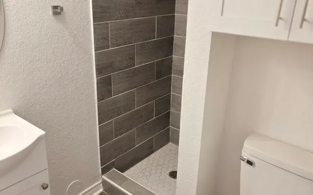 Modern Bathroom Interior A small bathroom featuring a modern shower, toilet, and sink with wooden flooring.