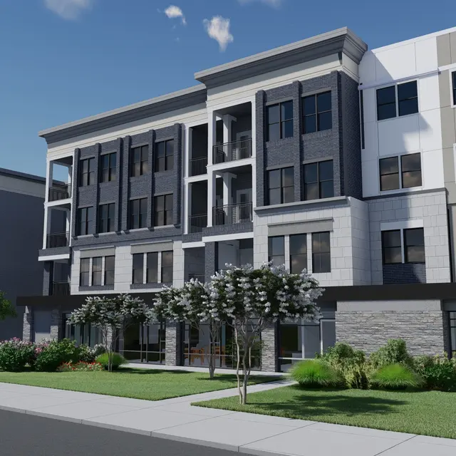 A modern apartment building with multiple floors, featuring a mix of grey and white exterior finishes. The building has large windows, balconies, and landscaping with trees and grass in the foreground.