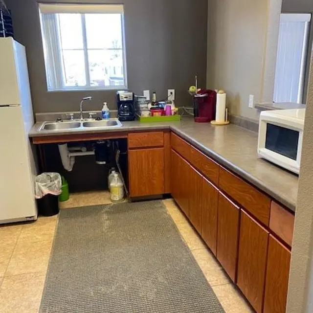 Modern Kitchen Interior A modern kitchen with wooden cabinets, a sink, a refrigerator, and a microwave, featuring a window allowing natural light to enter.