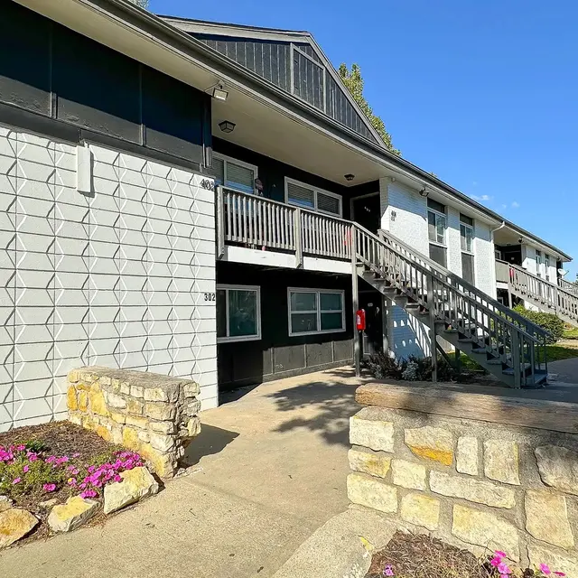 Apartment Complex Exterior Exterior of an apartment complex with a staircase leading to upper units and flowering plants in the foreground.