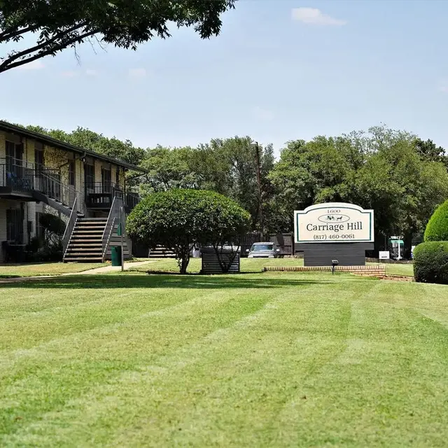 Apartment complex named Carriage Hill with landscaped lawns and trees
