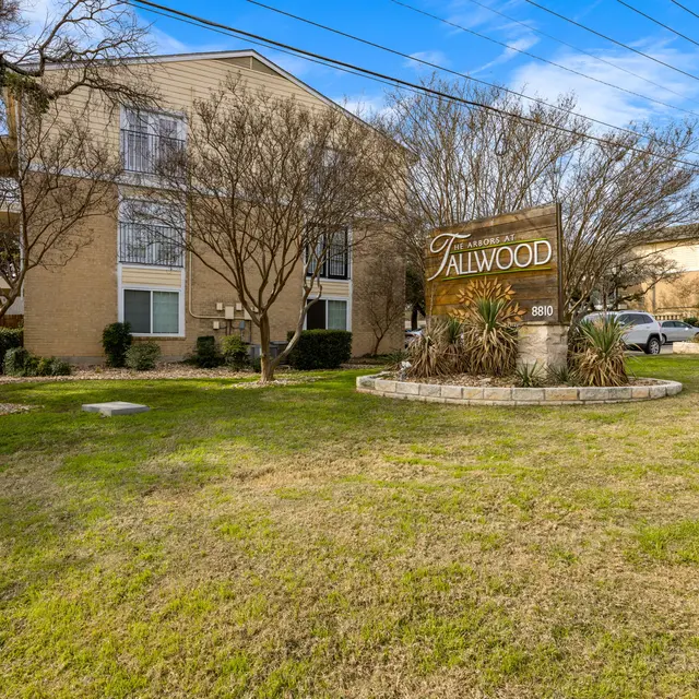 Sign for Fallwood apartments in a landscaped area with grass and trees.