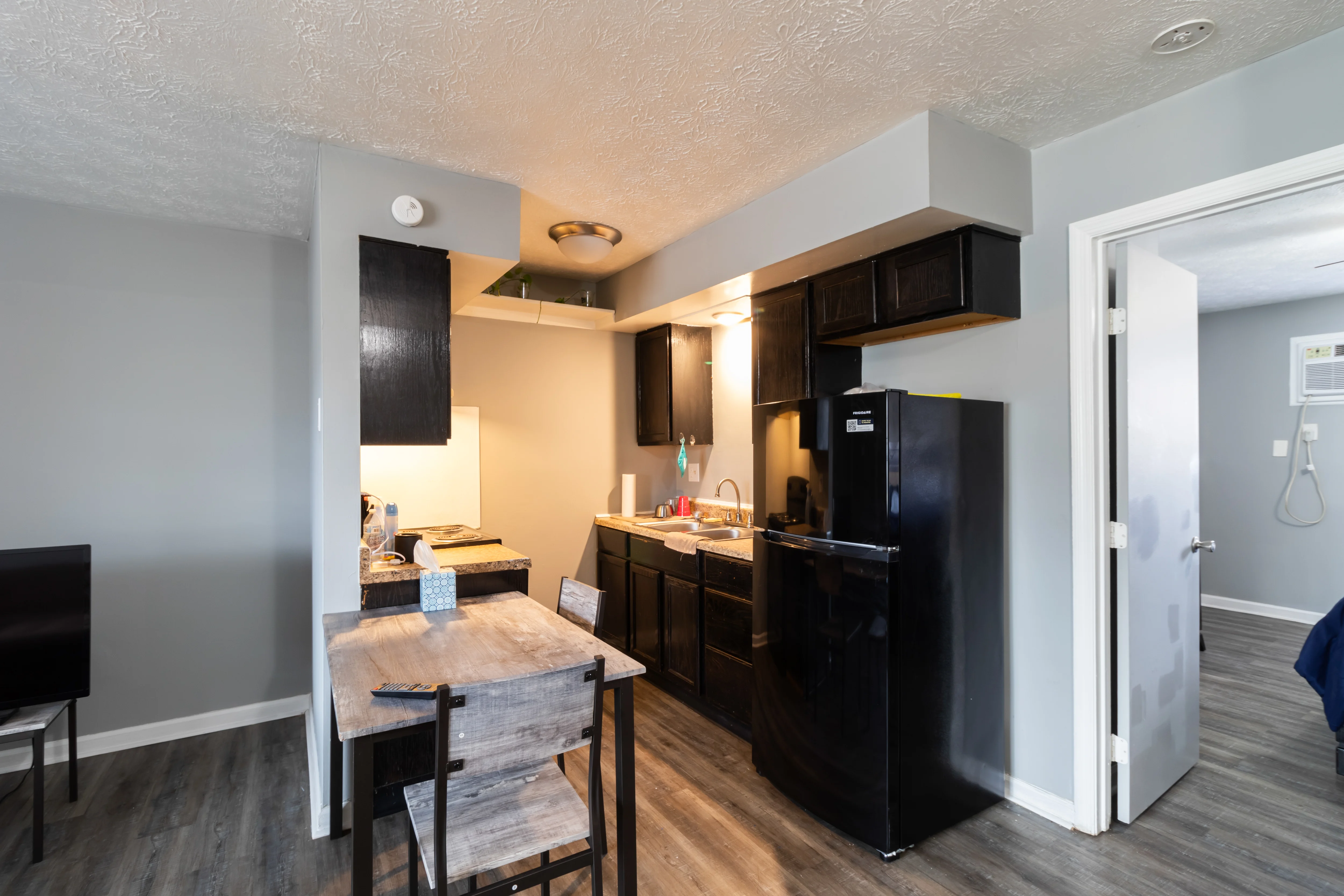 A modern kitchen with dark cabinets and a small dining table.