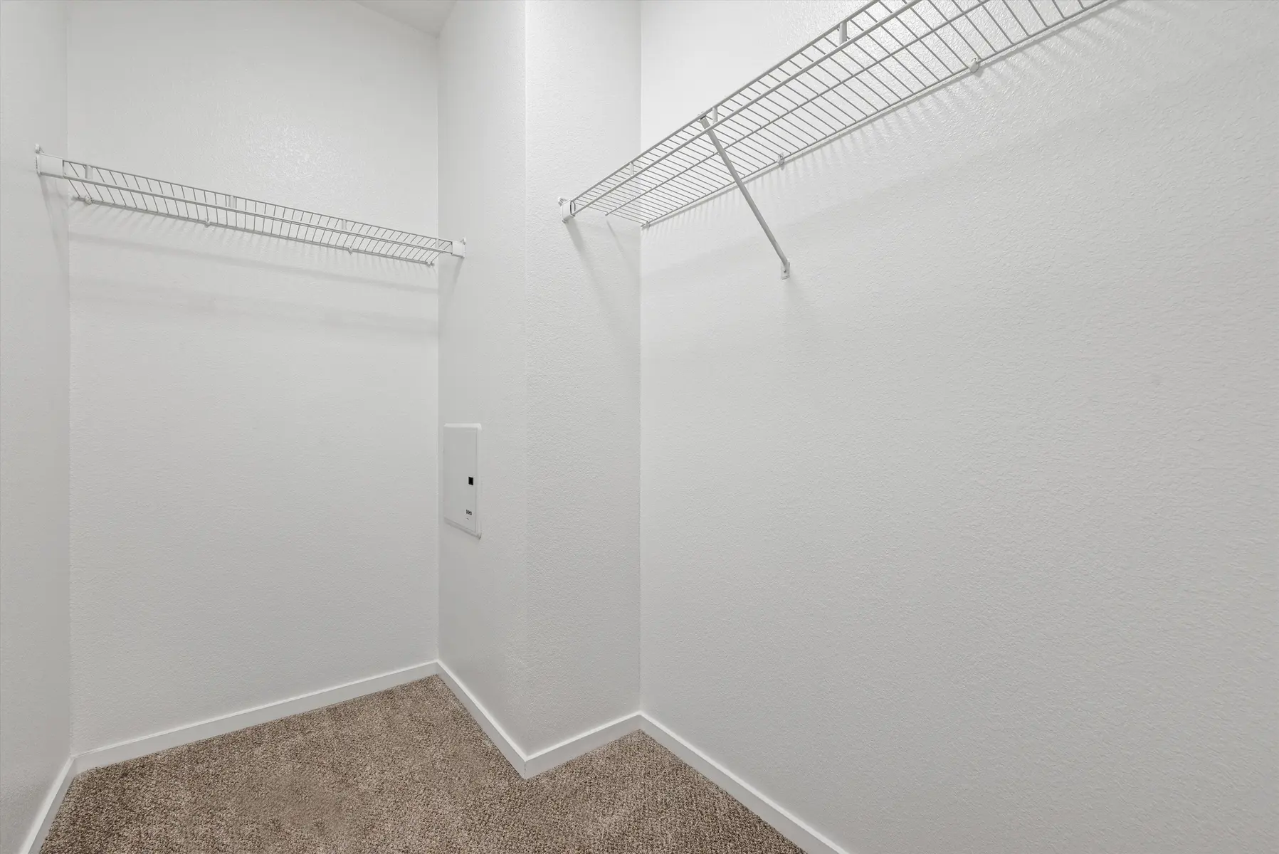 An empty closet featuring white walls and two wire shelving units.