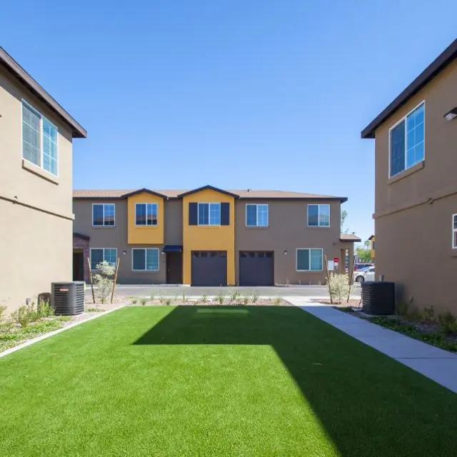 View of new townhouses with a green lawn and clear blue sky