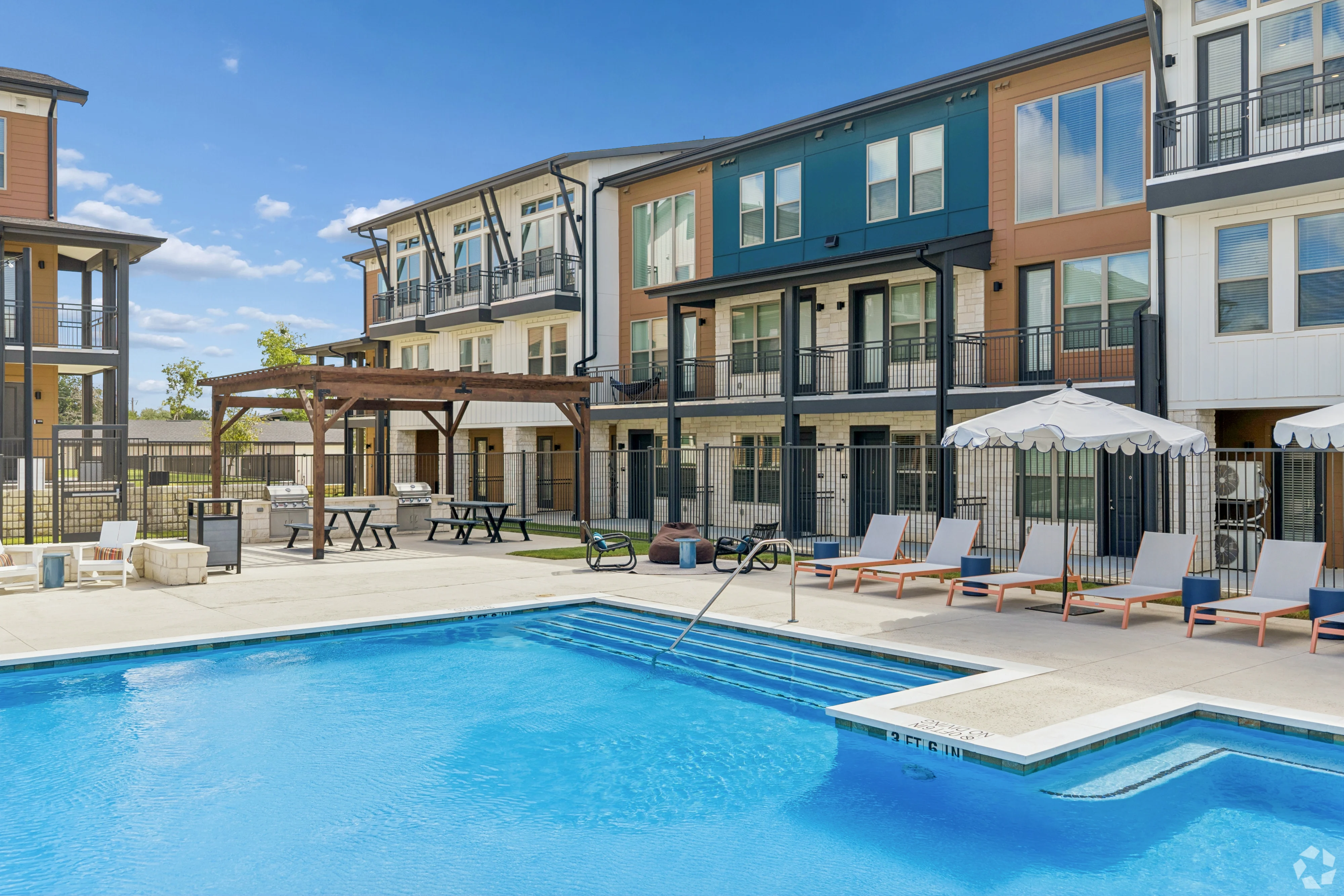 Modern Apartment Pool Area Outdoor pool area with seating and apartment buildings in the background.