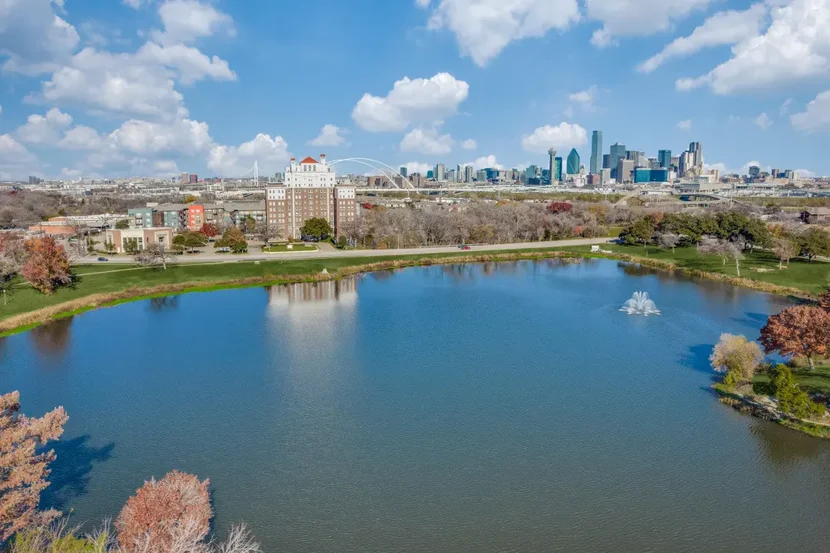 Lake View with City Skyline Aerial view of a lake in a park with a city skyline in the background under a partly cloudy sky.