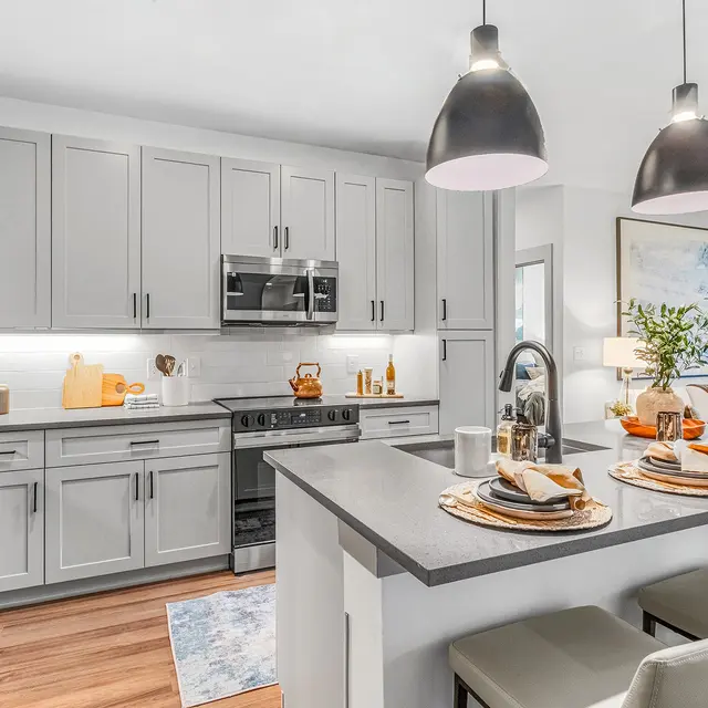 A modern kitchen featuring sleek cabinets, stainless steel appliances, and a stylish dining area with plates and utensils set on a countertop.