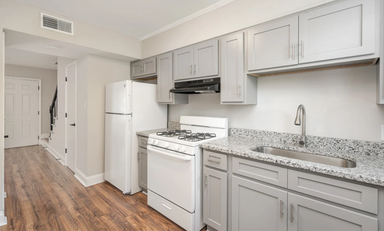 Stylish Gray Kitchen A modern kitchen featuring gray cabinets, a white stove, and a fridge, with granite countertops and wood-like flooring.
