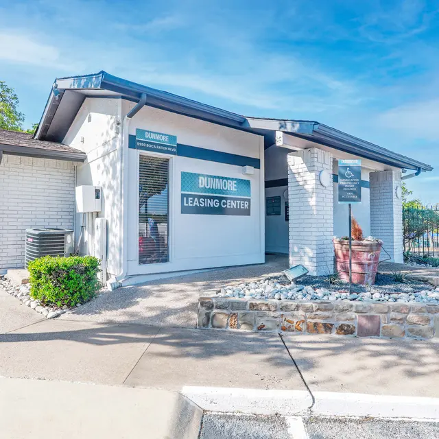 Exterior view of the Dunmore Leasing Center, featuring a modern building with a sign displaying 'Dunmore Leasing Center', surrounded by landscaping and decorative stone.