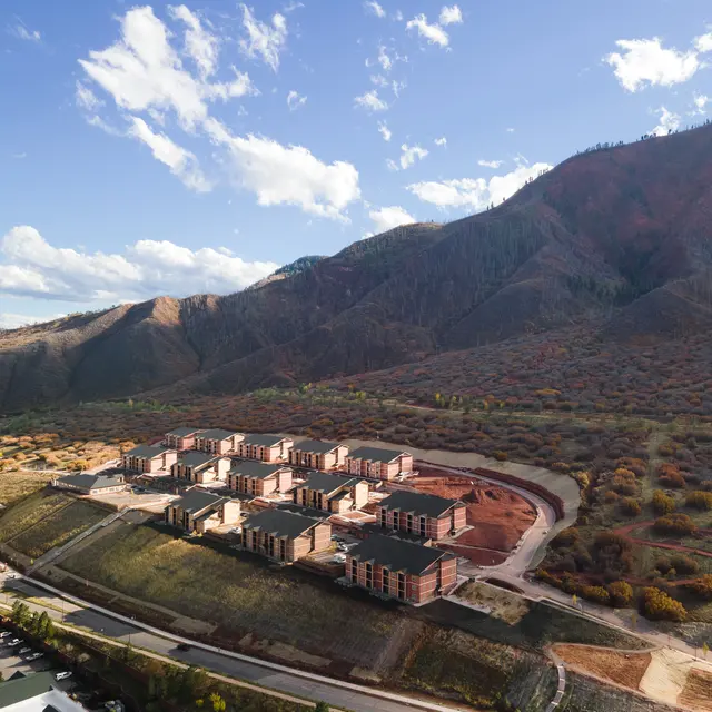 Aerial view of an incomplete condominium project set against a mountainous landscape with a mix of trees.