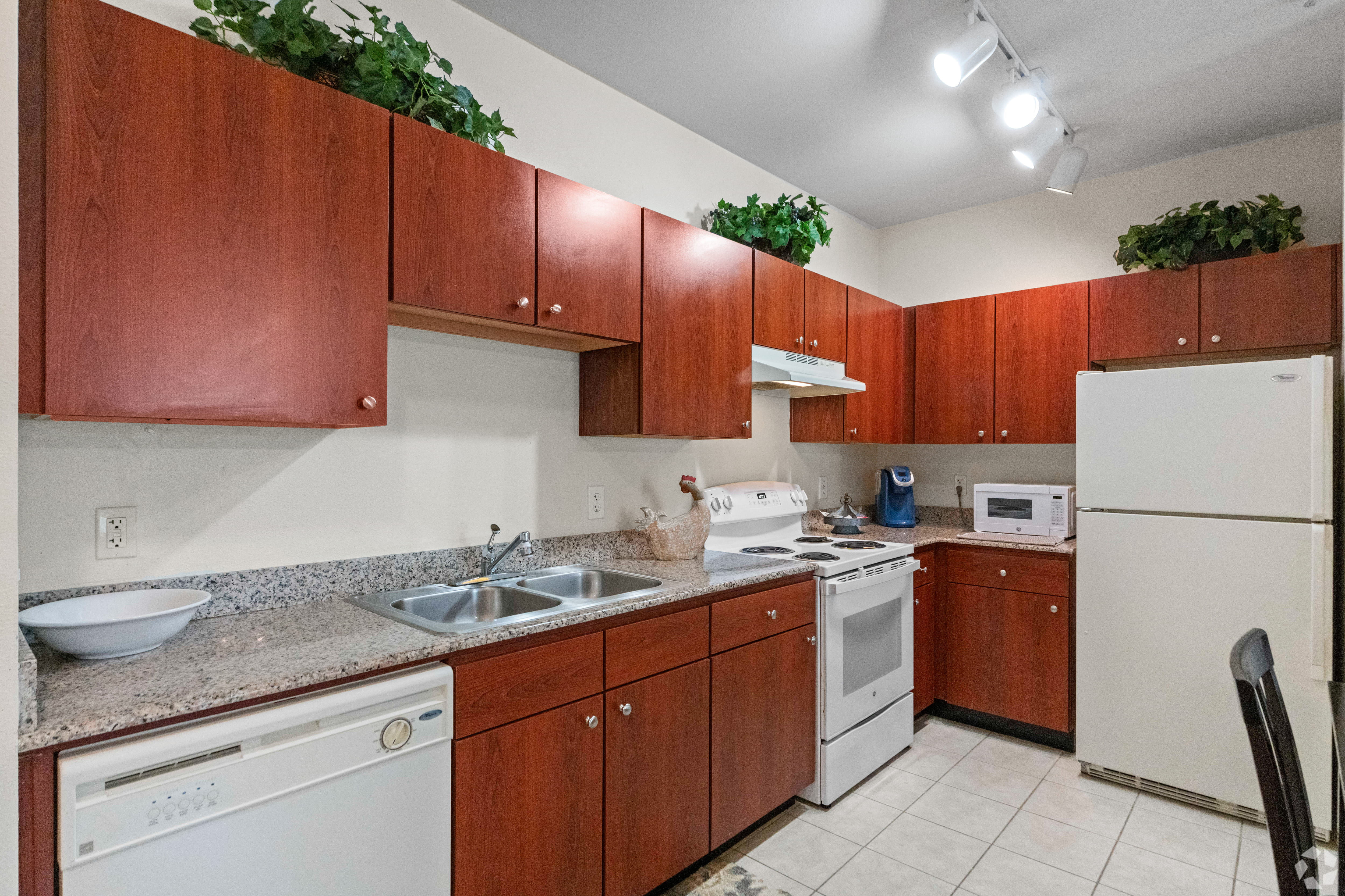 Modern Kitchen Design A modern kitchen featuring wooden cabinets, a white countertop, appliances including a refrigerator, stove, microwave, and dishwasher.