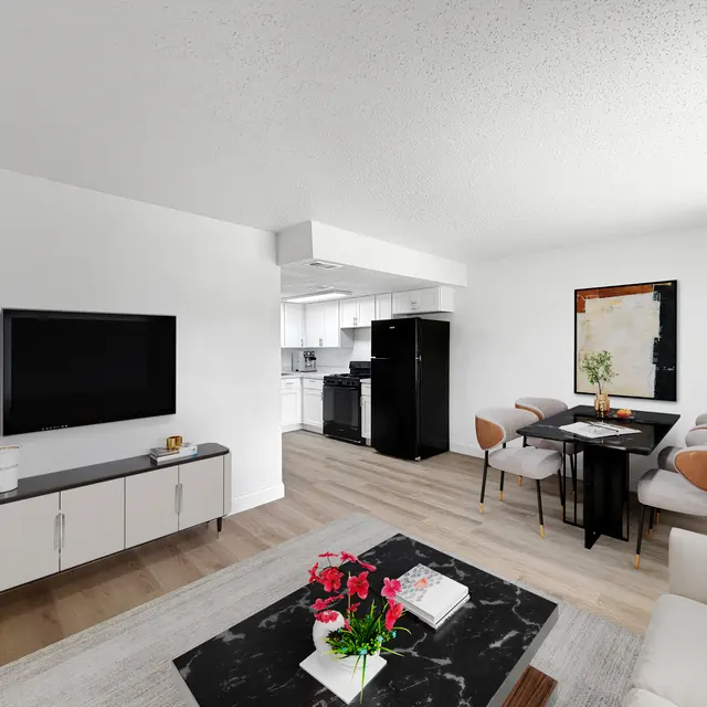 Modern Apartment Living Area A modern living area featuring a light-colored sofa, a black and white marble coffee table, a television mounted on the wall, and a dining area with a black table and beige chairs.