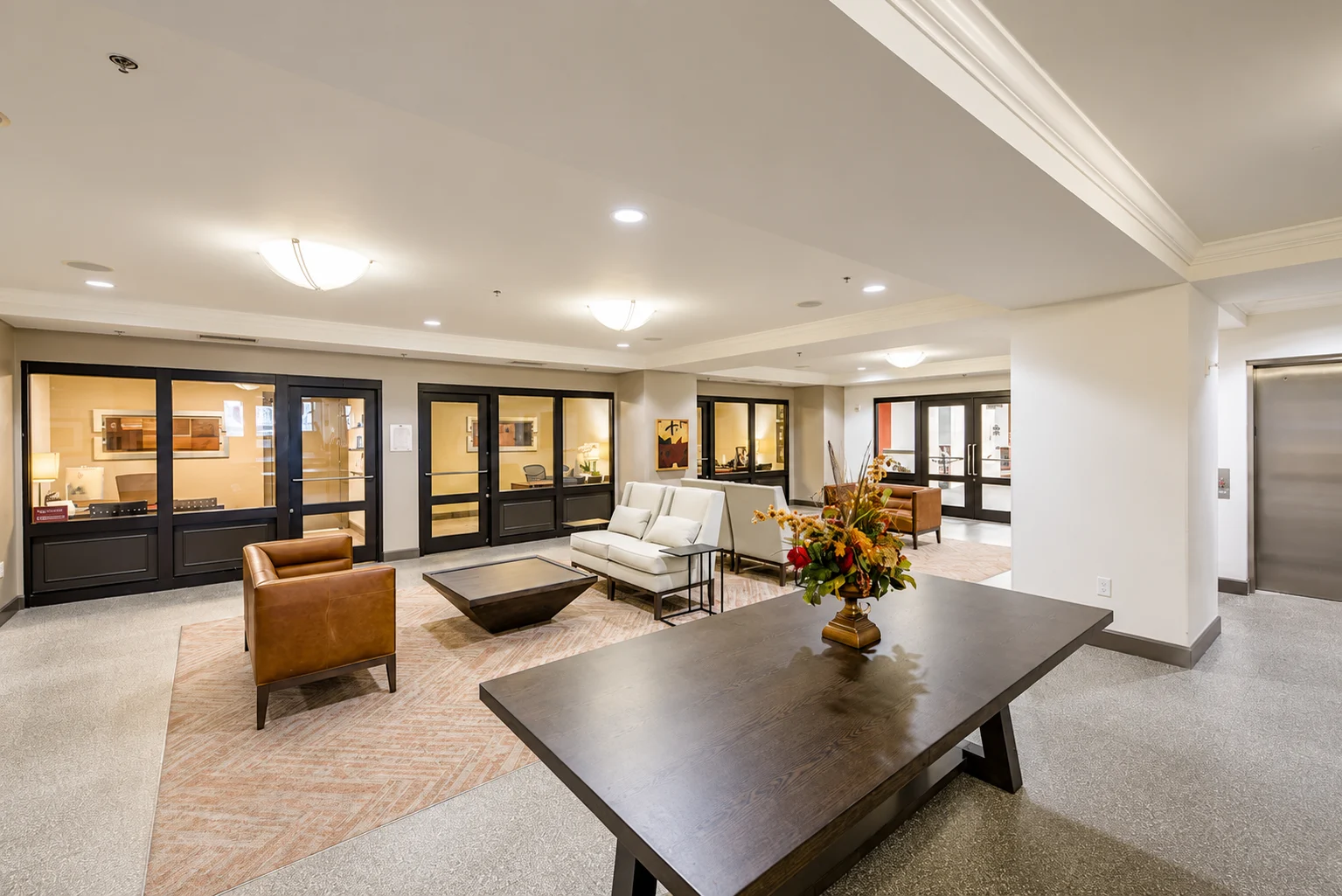 Interior view of a community lobby with seating areas, a coffee table, and decorative flowers.