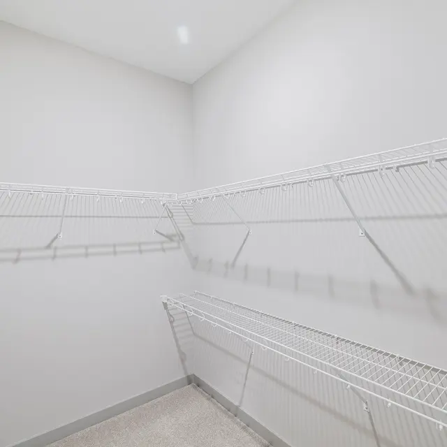 An empty closet with white wire shelving against light gray walls.