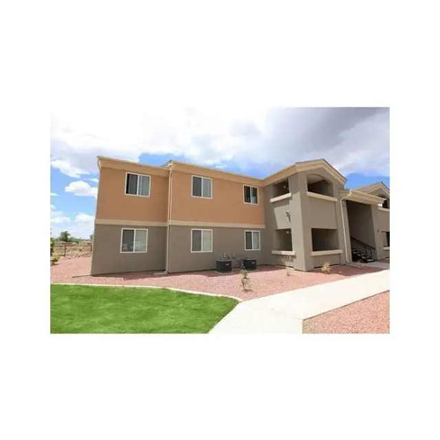 Apartment Complex Exterior View Exterior view of an apartment building with two levels, featuring tan and brown walls, with a sidewalk and green grass in the foreground.