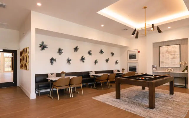 A modern lounge area featuring a pool table, seating, wall art, and contemporary decor.