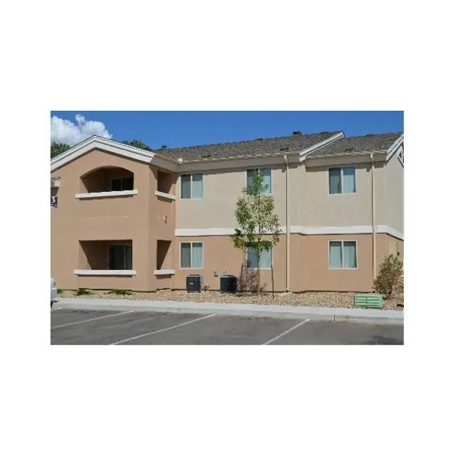 Exterior view of a two-story apartment building with beige and light brown siding and several windows.