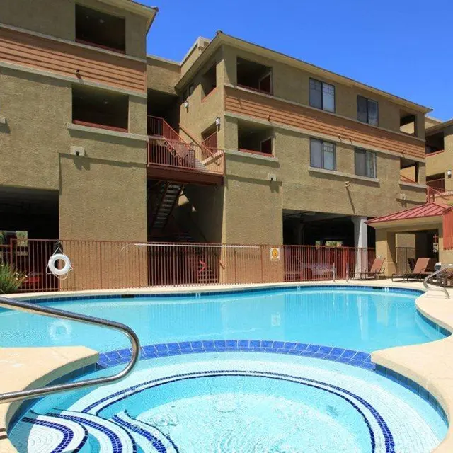 Swimming Pool Area A bright swimming pool area surrounded by apartments, featuring a hot tub and lounge chairs.