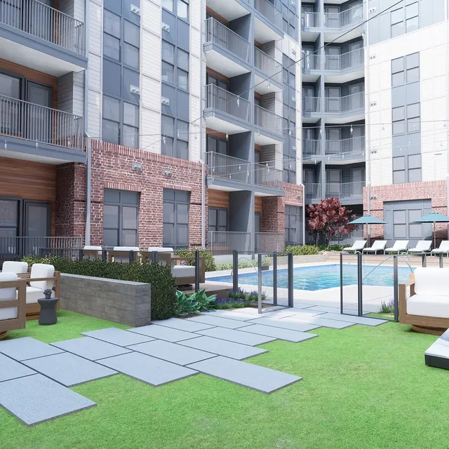 A modern apartment complex courtyard featuring a pool, lounge chairs, and green landscaping.
