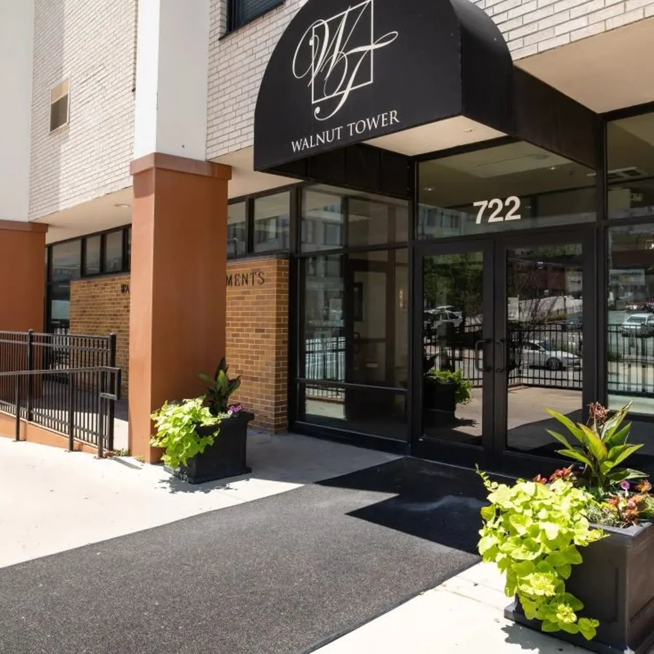 Walnut Tower Entrance Entrance to Walnut Tower, featuring a black canopy and planters with green plants, on a sunny day.