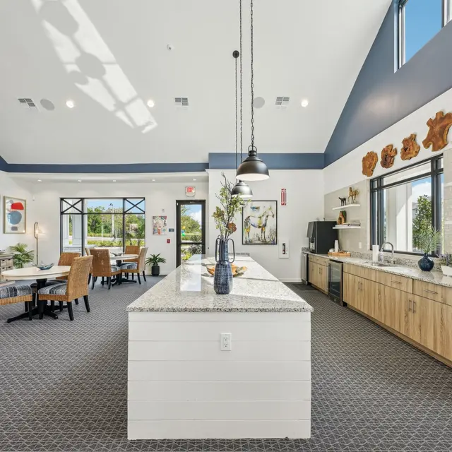 Modern Common Area Bright, modern common area with large windows and stylish decor. Features a central island with seating, kitchen area on one side, and various dining tables.