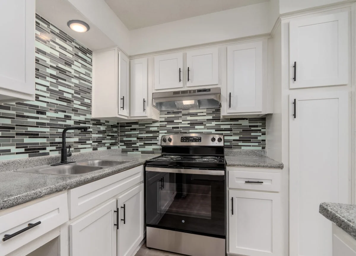 Modern Kitchen Design A modern kitchen featuring white cabinetry, stainless steel appliances, and a backsplash of small green and gray tiles.