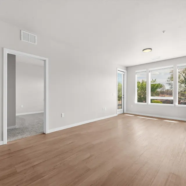 Spacious, modern living room with large windows and light wood flooring