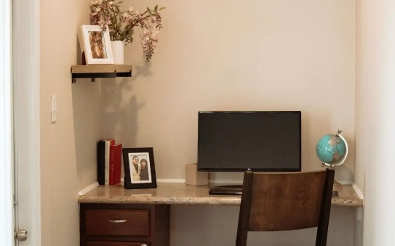 Cozy Home Office Corner A small home office corner featuring a desk with a computer monitor, a brown chair, and decorative items on the shelf.