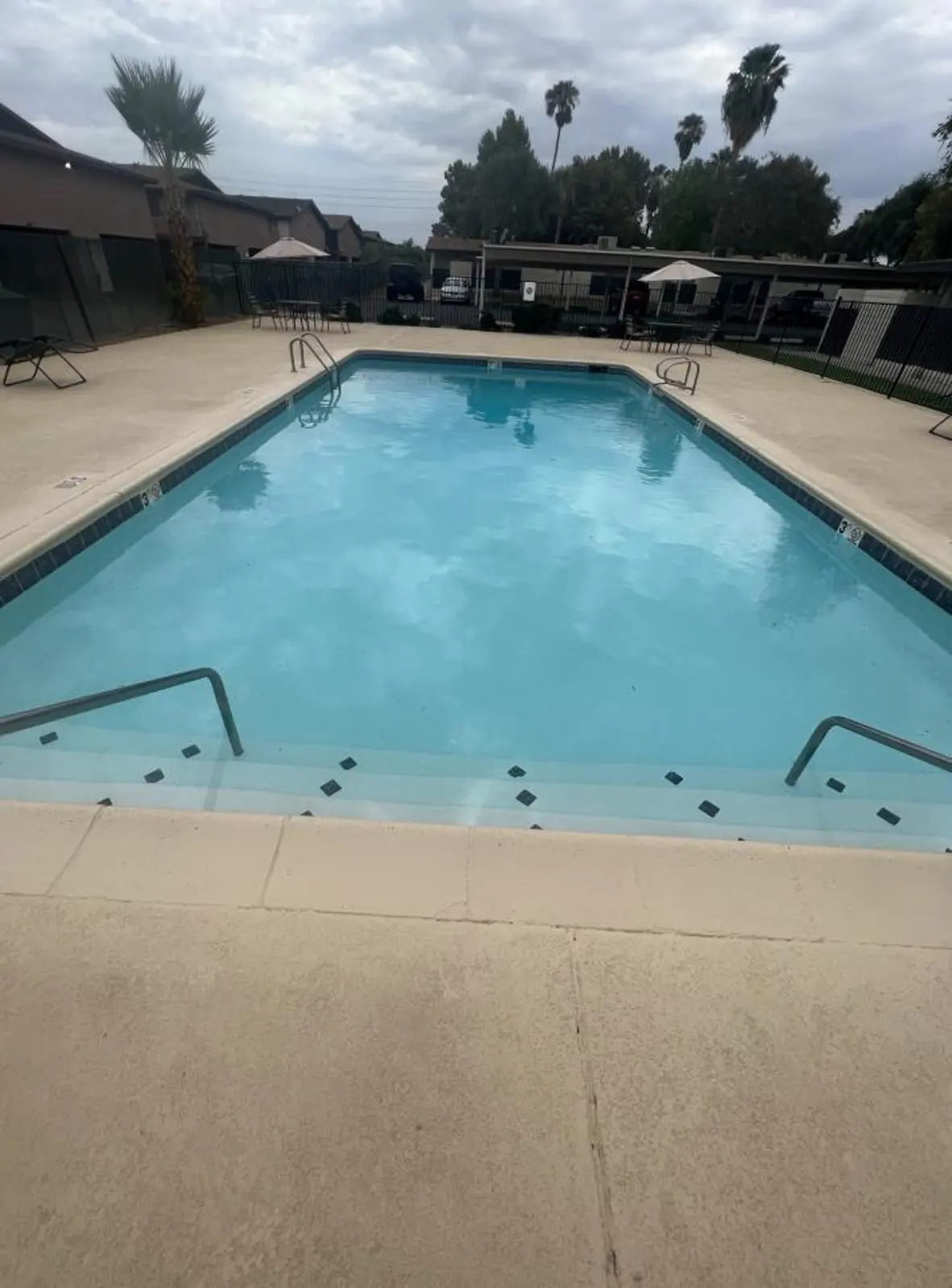 Swimming pool with entry rails and surrounding apartment buildings.