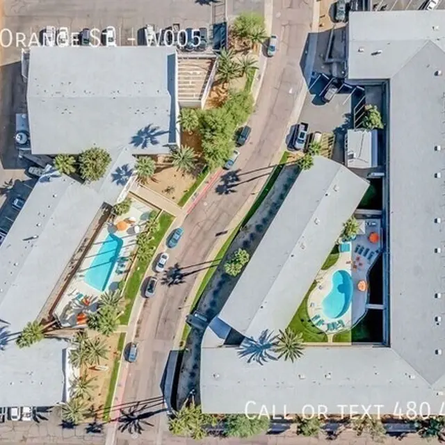 Aerial view of an apartment complex featuring pools and parking areas.