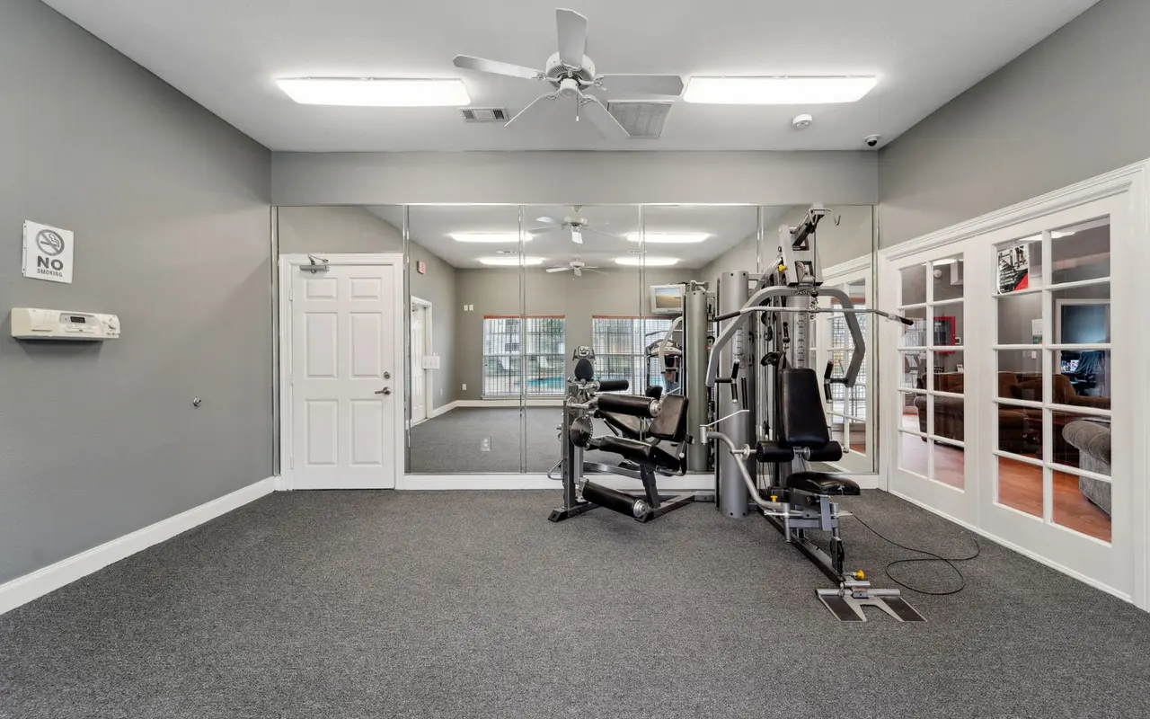 Interior view of a gym with exercise equipment and a mirrored wall