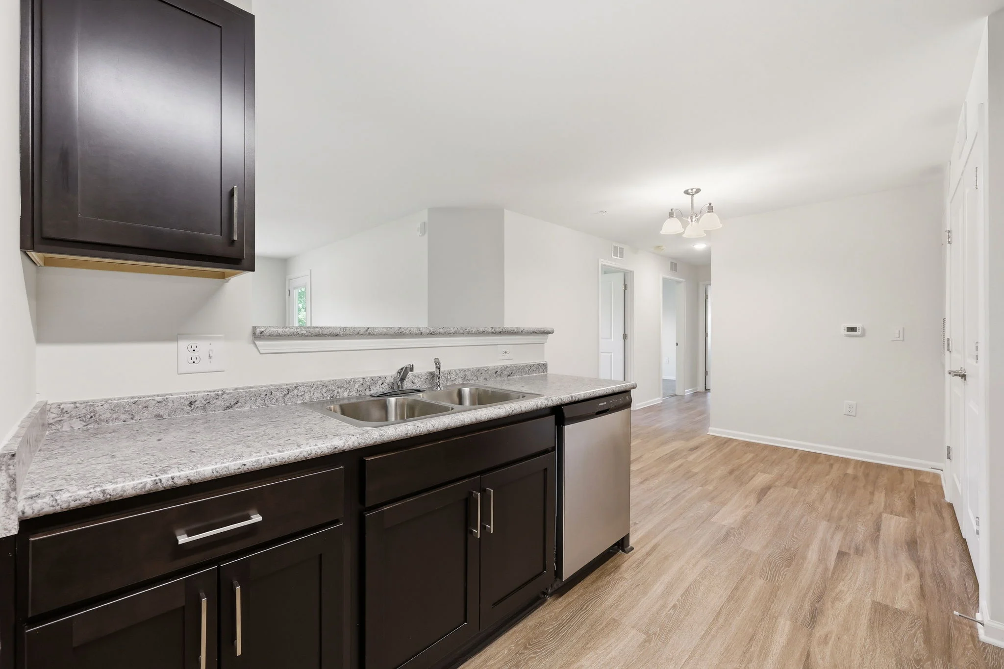 A modern kitchen with dark cabinetry, stainless steel appliances, and a granite countertop
