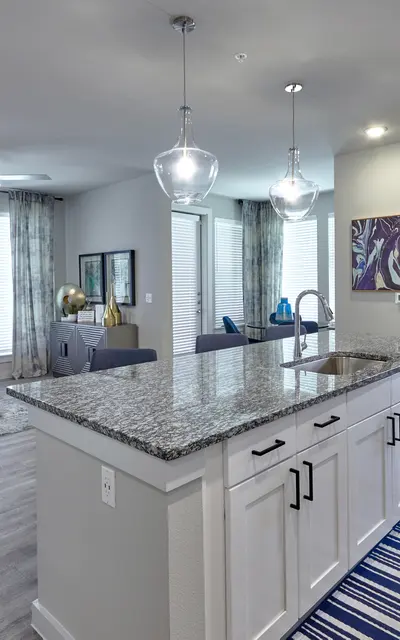 A modern apartment interior featuring a kitchen island, light wood flooring, and stylish, comfortable seating in a living area.