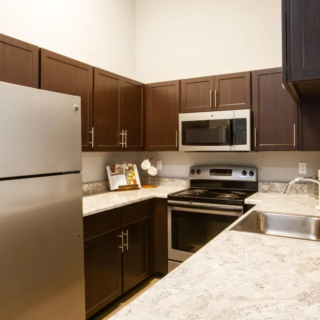 Updated apartment kitchen with dark cabinetry, black appliances, and open-concept layout at Centennial Crossing at Lenox Place