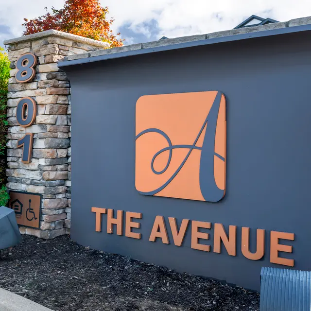 Sign for The Avenue, featuring stonework and a large orange logo with stylized 'A'.