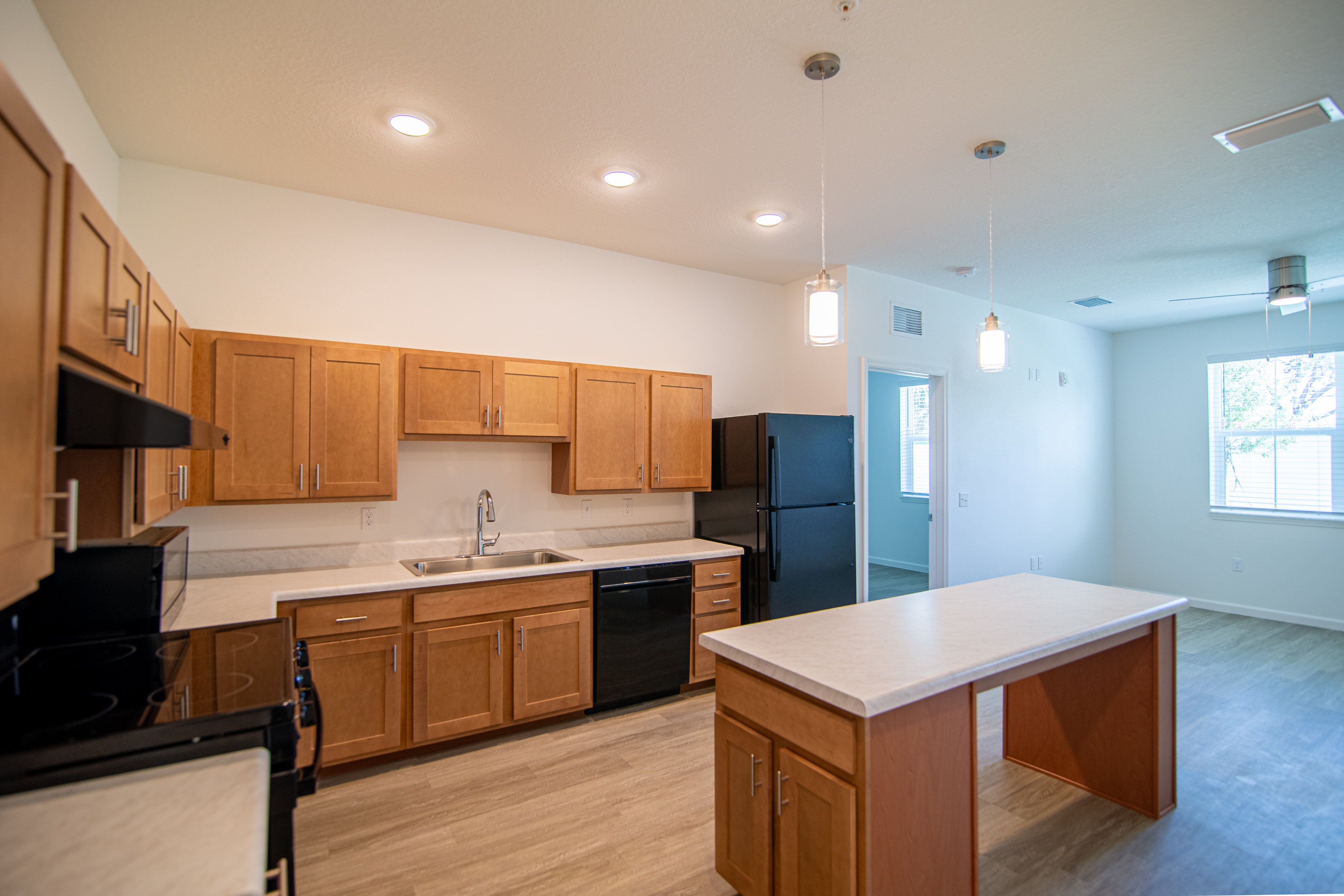 Modern Kitchen Design A modern kitchen featuring wooden cabinets, stainless steel sink, and black appliances. The layout includes a central island with seating space.