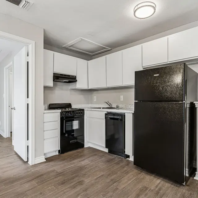 A modern kitchen with white cabinetry and black appliances including a refrigerator and dishwasher.