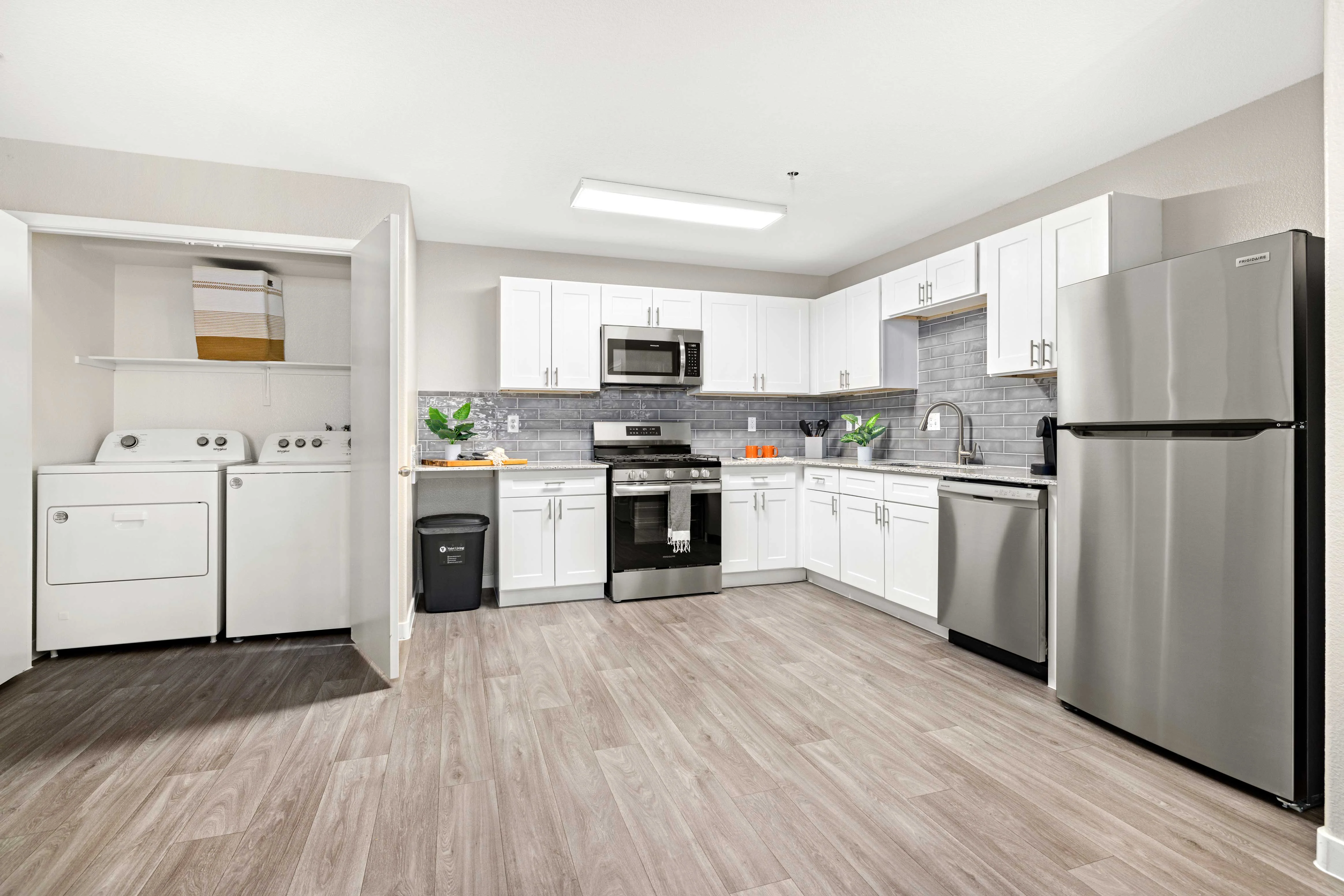 Spacious Modern Kitchen with Laundry Area A modern kitchen featuring white cabinets, stainless steel appliances, and an adjoining laundry area with a washer and dryer.