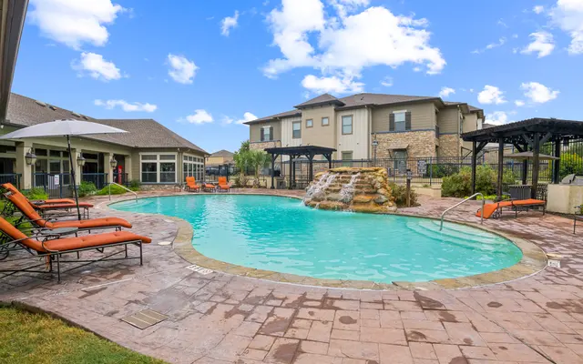 Luxury Apartment Pool Area A serene pool area with lounge chairs, surrounded by greenery and buildings.