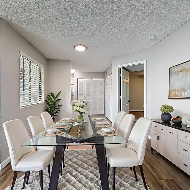 Modern Dining Room Interior Modern dining room with a glass table surrounded by white chairs, a decorative plant, and a sideboard.