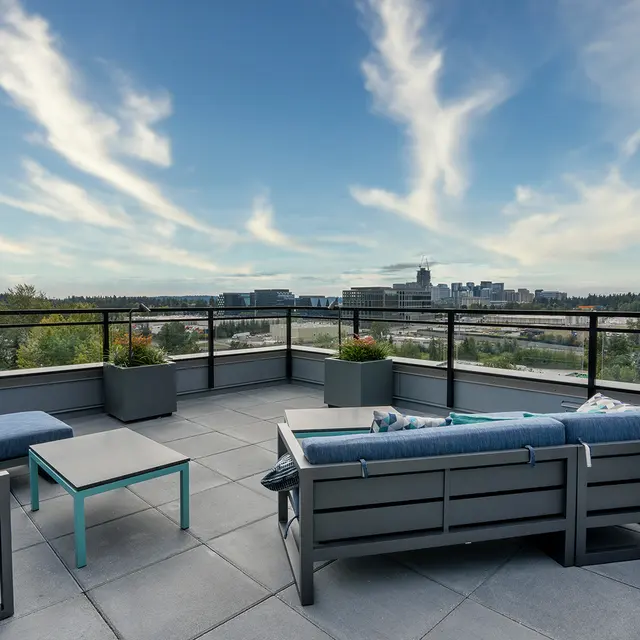 Rooftop Lounge with City View A serene rooftop lounge area with modern furniture, overlooking a city skyline and lush greenery under a dramatic sky.