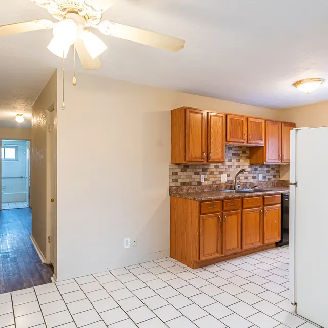Modern Kitchen Interior A clean kitchen with wooden cabinets and a tile floor. The kitchen is open to a hallway leading to other rooms.