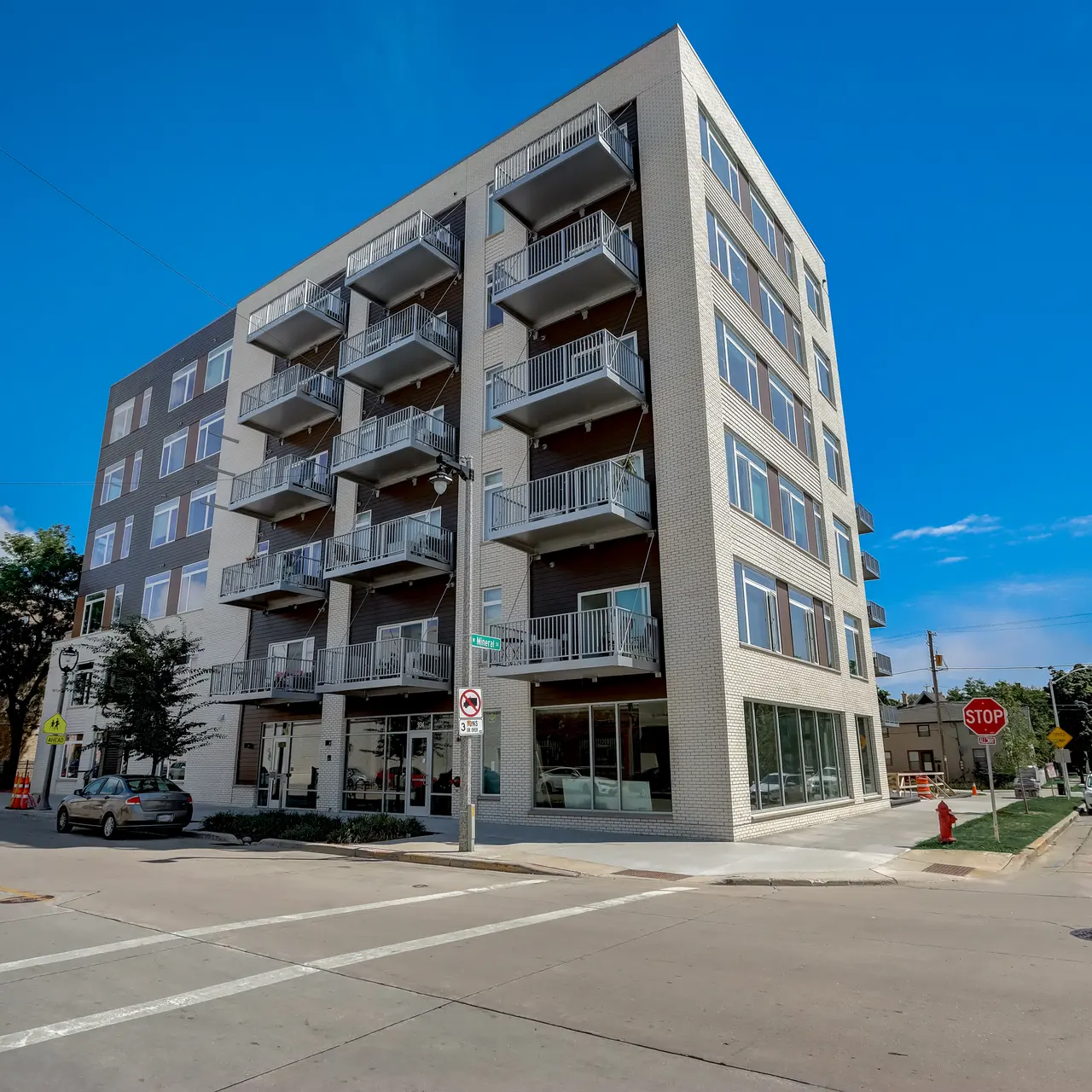 Element Apartments A modern apartment building with multiple balconies located at a street corner under a clear blue sky.